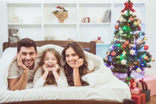 The smile family lay on the bed near the christmas tree