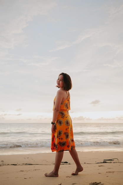 Sorriso libertà e felicità donna asiatica sulla spiaggia si sta godendo la natura serena dell'oceano durante il viaggio