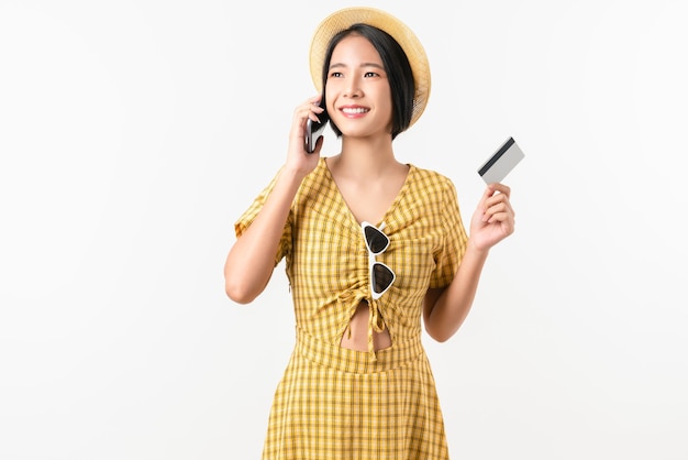 Smile happily Asian woman yellow dress holding smartphone and credit card shopping online on white background.