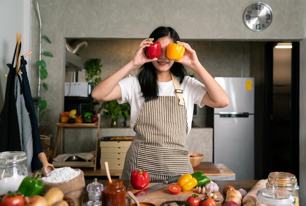 写真 笑顔の幸せなアジアの女性シェフは、キッチンで健康的な食事を調理するために新鮮な栄養野菜を保持します