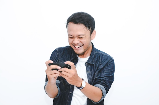 Smile and happy face of Young Asian man when playing game at phone in hand