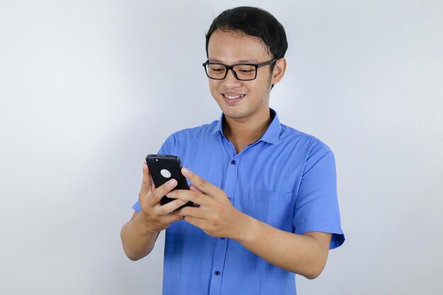 Улыбка и счастливое лицо молодого азиата с телефоном в руке Концепция рекламной модели с синей рубашкой