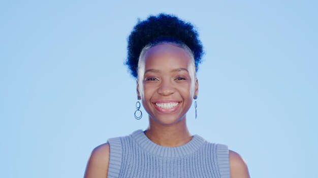smile happy and portrait of black woman in a studio with positive confident and good attitude excited pride and young african female model with joy and happiness isolated by blue background