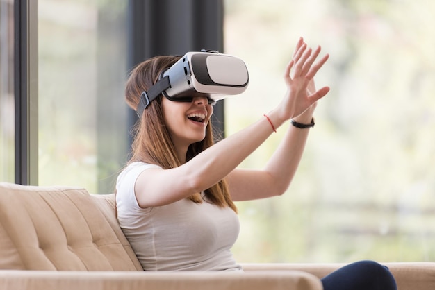 집에서 가상 현실의 VR 헤드셋 안경을 사용하여 경험을 얻는 행복한 여성 미소