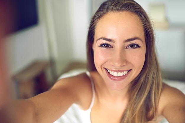 smile its saturday shot of a young woman taking a morning selfie at home
