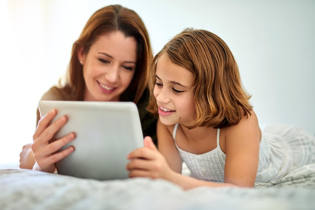 母と子がテーブレットで一緒に遊びリラックス家族のストリーミング映画を楽しむ 幸せな女の子母親とテクノロジー学習教育またはアプリで電子書籍をオンラインで読むための寝室