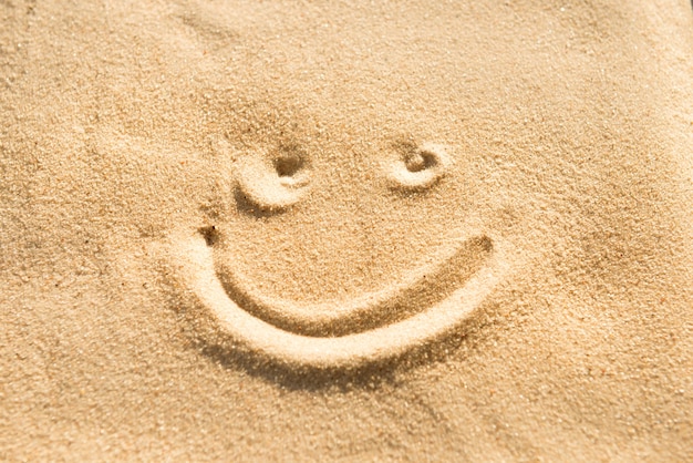 Segno di sorriso che disegna sulla sabbia della spiaggia