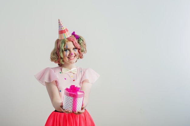 Sorriso ragazza adolescente in costume da clown con scatola regalo