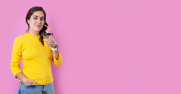 Smile woman drinking orange juice in isolated on pastel pink background