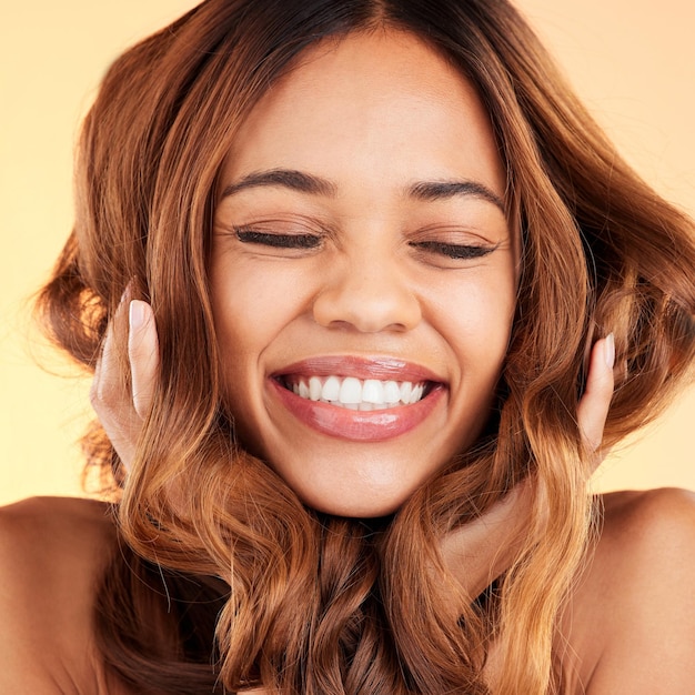 Foto sorriso donna e cura dei capelli per la lucentezza e la consistenza con la ragazza su uno sfondo da studio donna donna e trattamento da salone per la bellezza felicità e fiducia con la cura allegra e gioia