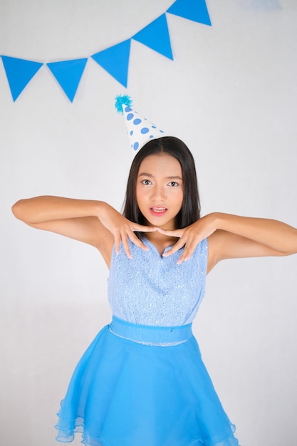 Smile young girl wear blue dress and a party hat on white background