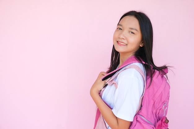 Smile young girl with backpack on pink background