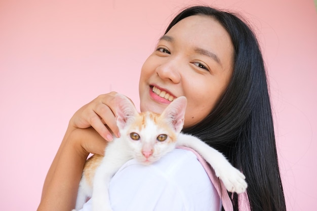 Smile young girl with cat on pink background