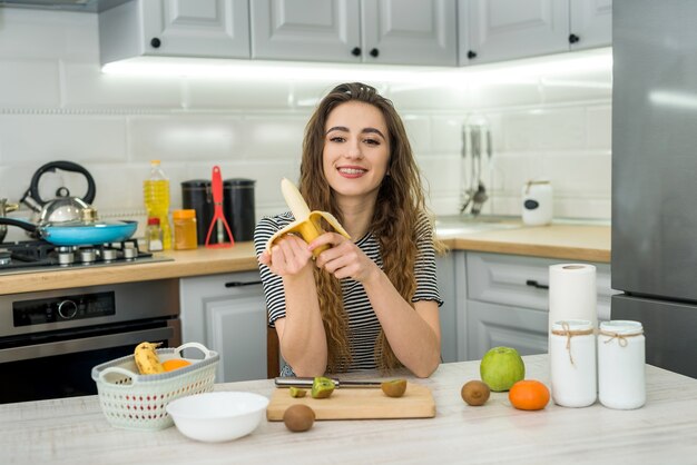 Smile young woman cooking fresh salad with fruit in kitchen. Healthy lifestyle. Diet