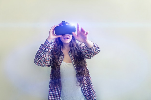 Фото Молодая женщина улыбки нося используя шлемофон шлема стекел виртуальной реальности vr на белой предпосылке. использование смартфона с очками виртуальной реальности