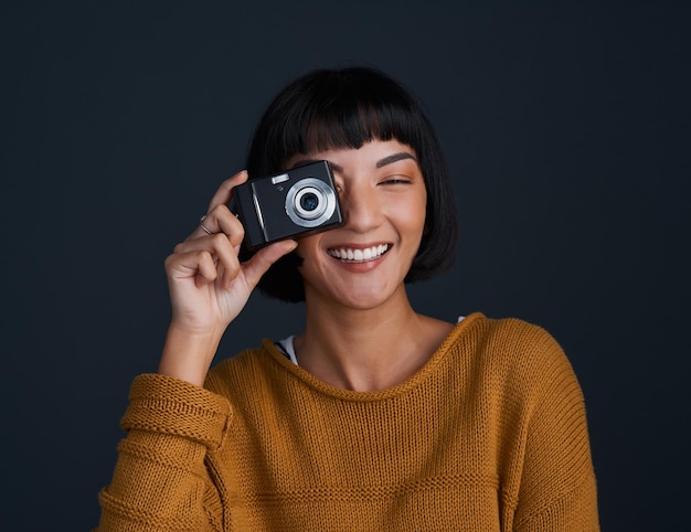 写真 暗い背景にカメラを使用して若い女性のカメラスタジオポートレートであなたを笑顔