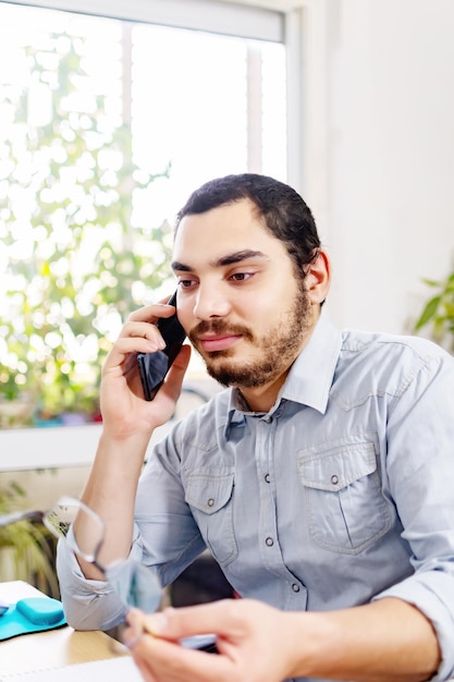 Улыбающийся взрослый мужчина разговаривает со своим начальником по телефону