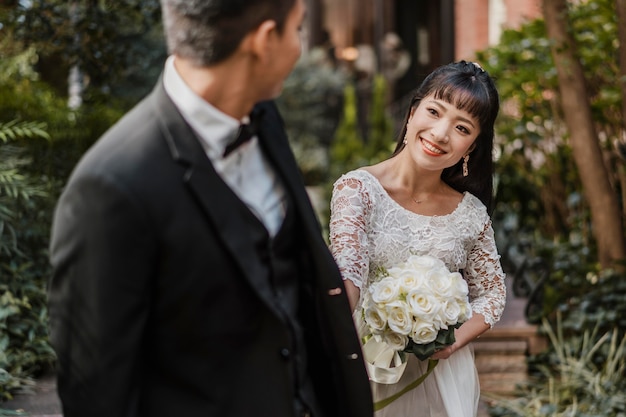 Smiley bride with bouquet looking at the groom