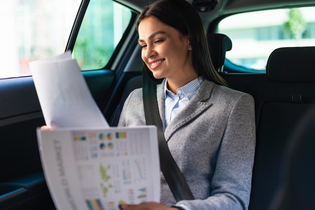 Photo smiley businesswoman in the car reviewing documents