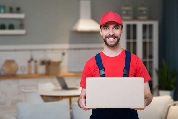 Photo smiley delivery man posing while holding box