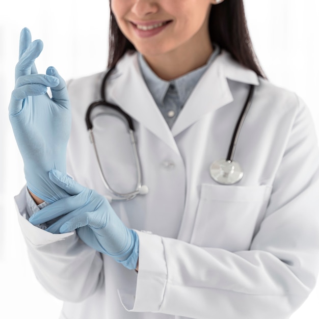 Photo smiley doctor putting on surgical gloves