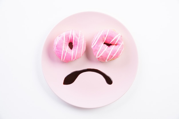 Foto smiley droevig gezicht bezorgd over overgewicht gemaakt op schotel met donuts