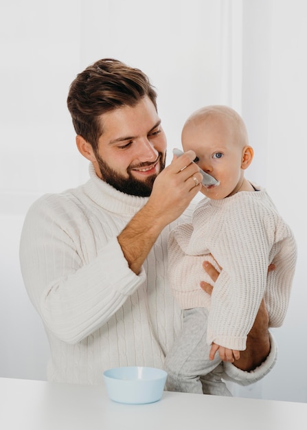 smiley father giving food to his baby