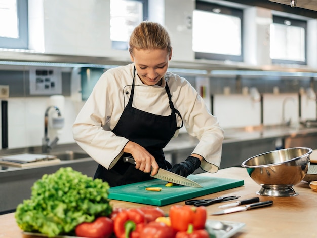 写真 キッチンで野菜を切るスマイリー女性シェフ