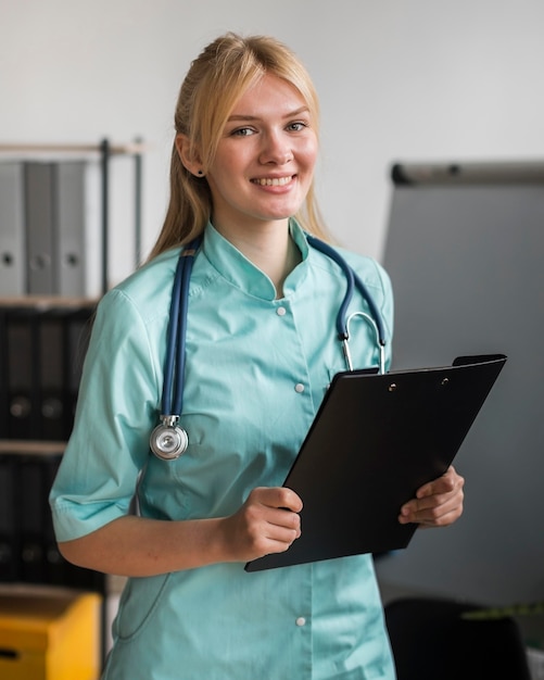 Photo smiley female nurse in the office with stethoscope and notepad