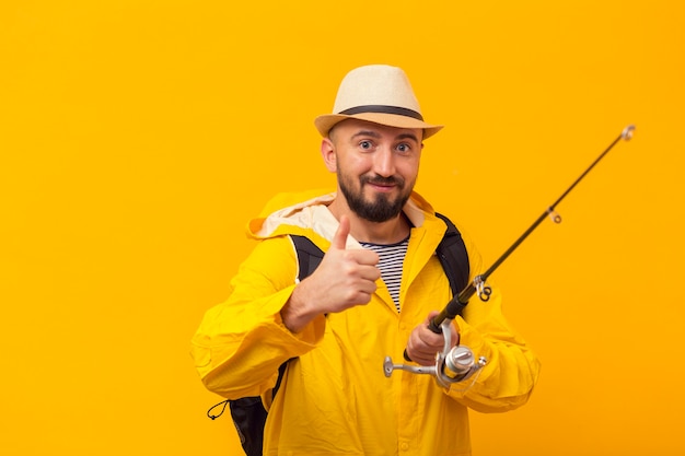 Foto pescatore di smiley che dà i pollici in su mentre tiene la canna da pesca