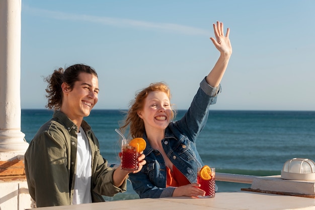 Smiley friends with sangria at seaside medium shot