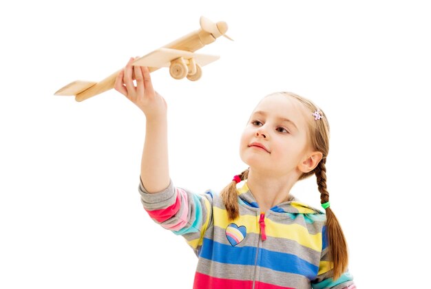 Smiley girl playing with wooden toy plane