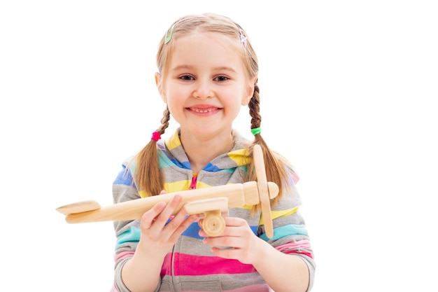 Smiley girl playing with wooden toy plane