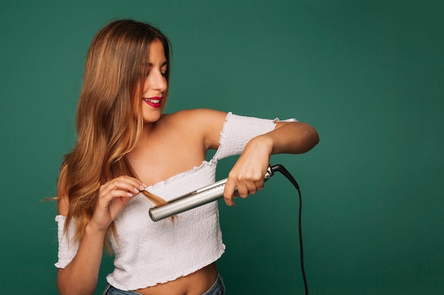 Photo smiley girl with hair straightener