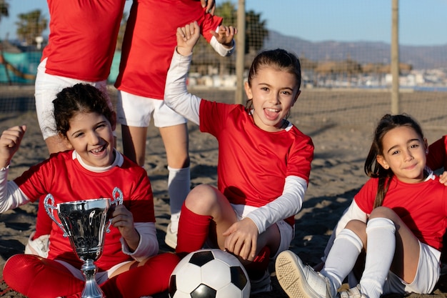 Smiley girls holding trophee on beach