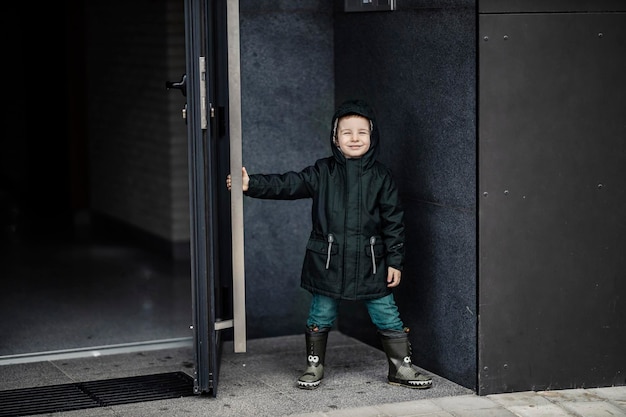 A smiley little boy is opening a building door for elders