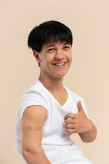 Smiley man showing arm with sticker after vaccine and giving thumbs up