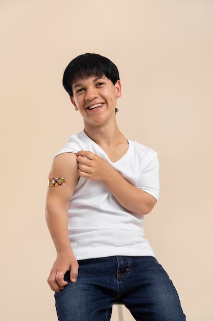 Smiley man showing sticker on arm after vaccine