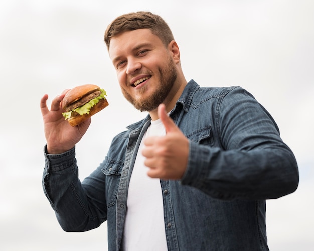 Foto uomo di smiley con hamburger che mostra approvazione