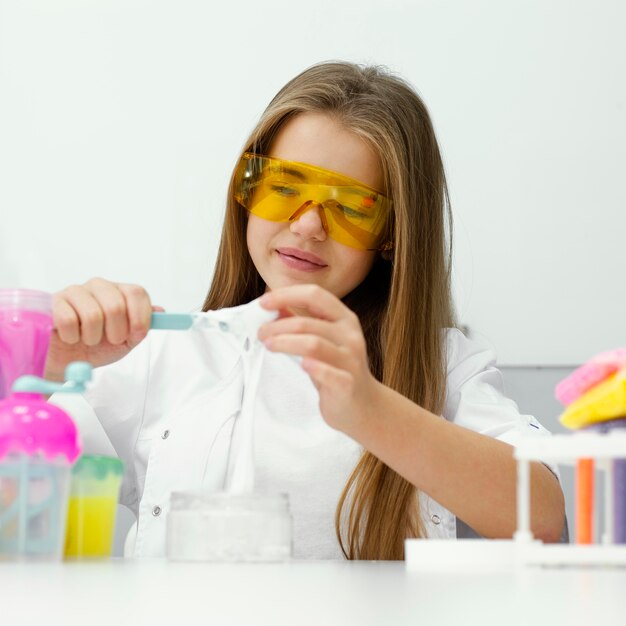 Smiley meisje wetenschapper met veiligheidsbril plezier maken van slijm in het lab