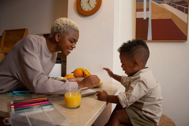 Photo smiley mother feeding baby side view