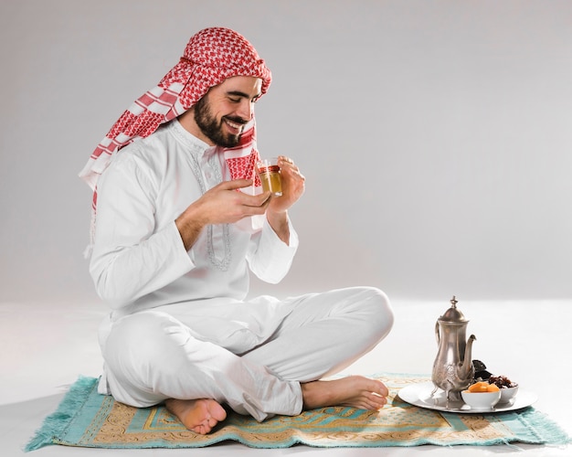 Foto l'uomo musulmano di smiley gode del tè tradizionale