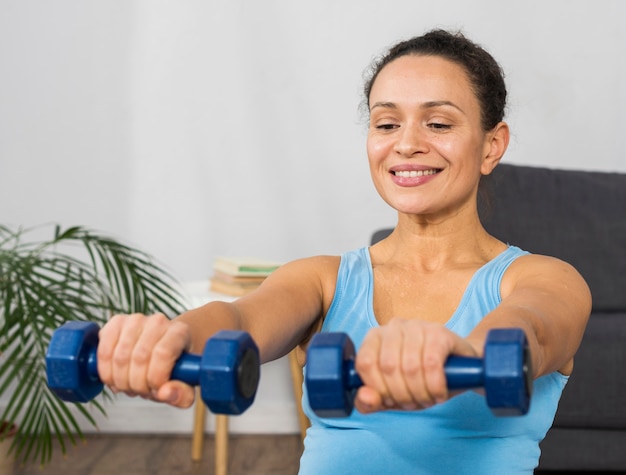 Photo smiley pregnant woman training with weights at home