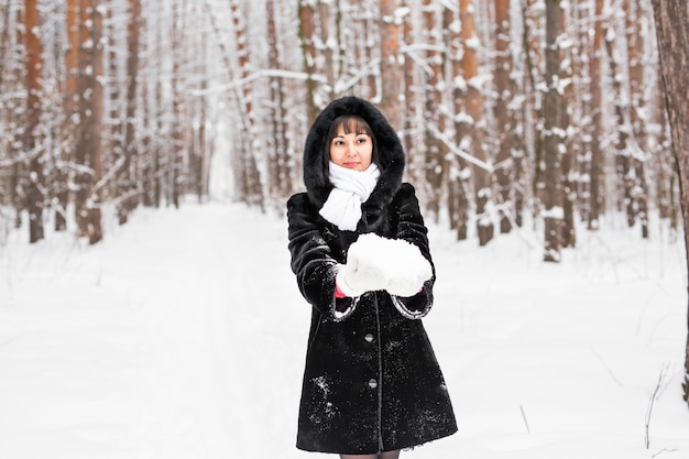 Smiley pretty woman holding snow in mittens.