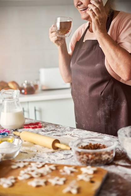 Foto donna anziana sorridente che fa una telefonata e sorseggia il tè