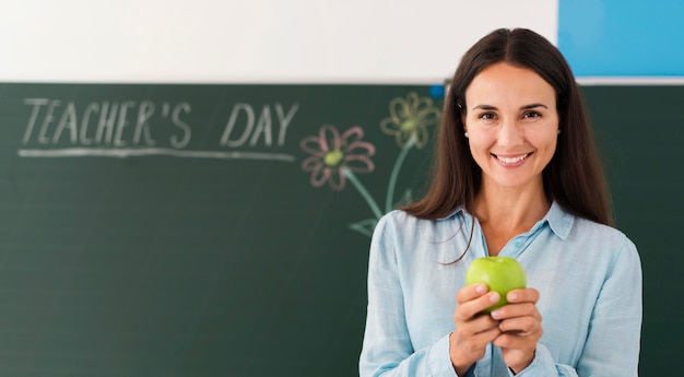 Smiley teacher holding an apple with copy space