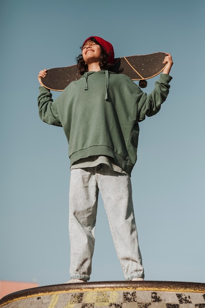 Smiley teenager at the skatepark having fun with skateboard