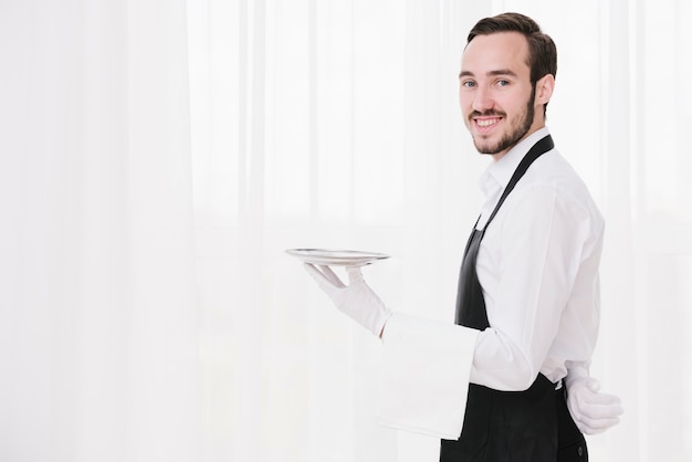 Photo smiley waiter with plate looking at camera