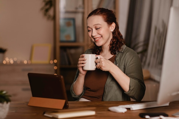 写真 自宅でコーヒーを飲み、タブレットを使用しているスマイリー女性