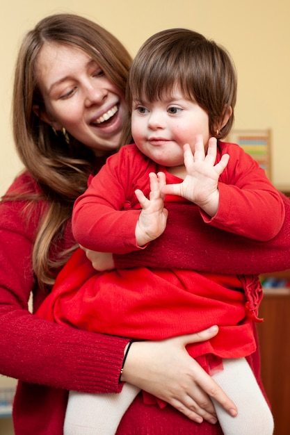 Photo smiley woman holding child with down syndrome